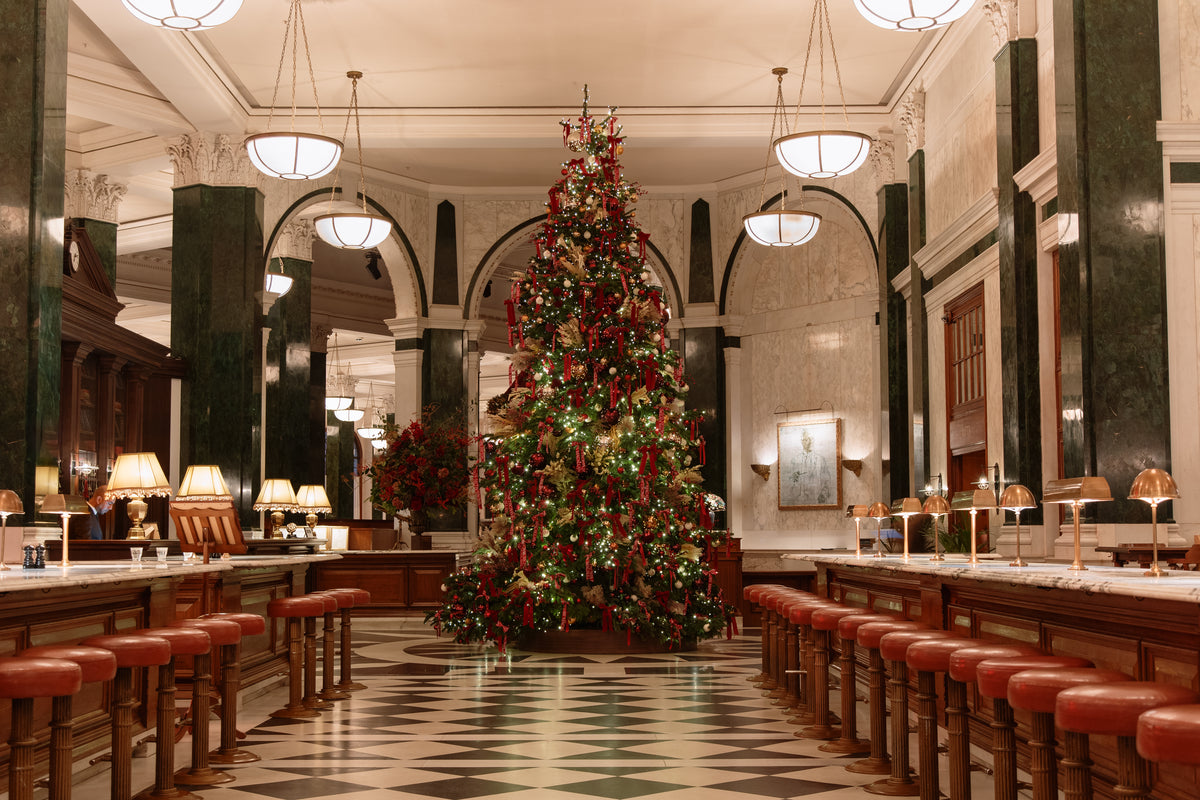 A Macallan-dressed Christmas tree viewed through a marble archway in The Ned's banking-hall lobby